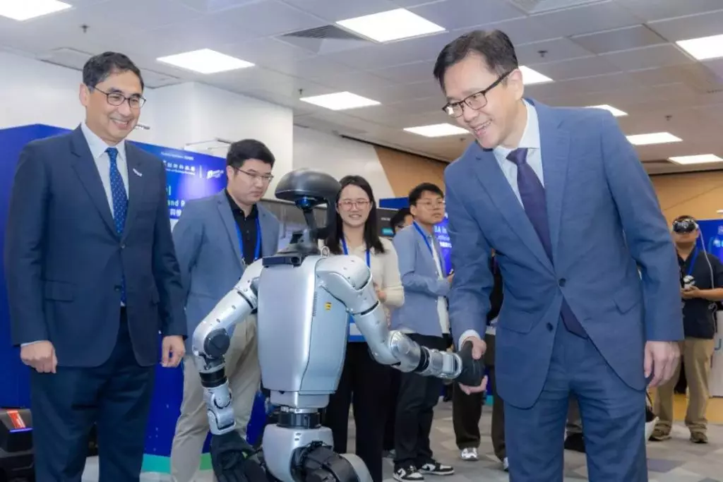 香港特別行政區政府創新科技及工業局局長孫東（右）在生產力局總裁畢堅文（左）陪同下，參觀展覽並與機器人互動。
