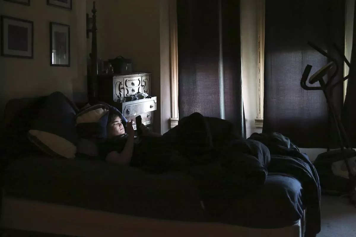 FILE - James Walter uses a phone at home in the Queens borough of New York, on April 7, 2021. Sleep scientists long ago established that insufficient sleep is linked with poor health outcomes, anxiety, obesity and several other negative effects. The research is equally conclusive that smartphones are particularly disruptive to the circadian clock that regulates sleep and other hormones. (AP Photo/Jessie Wardarski, File)