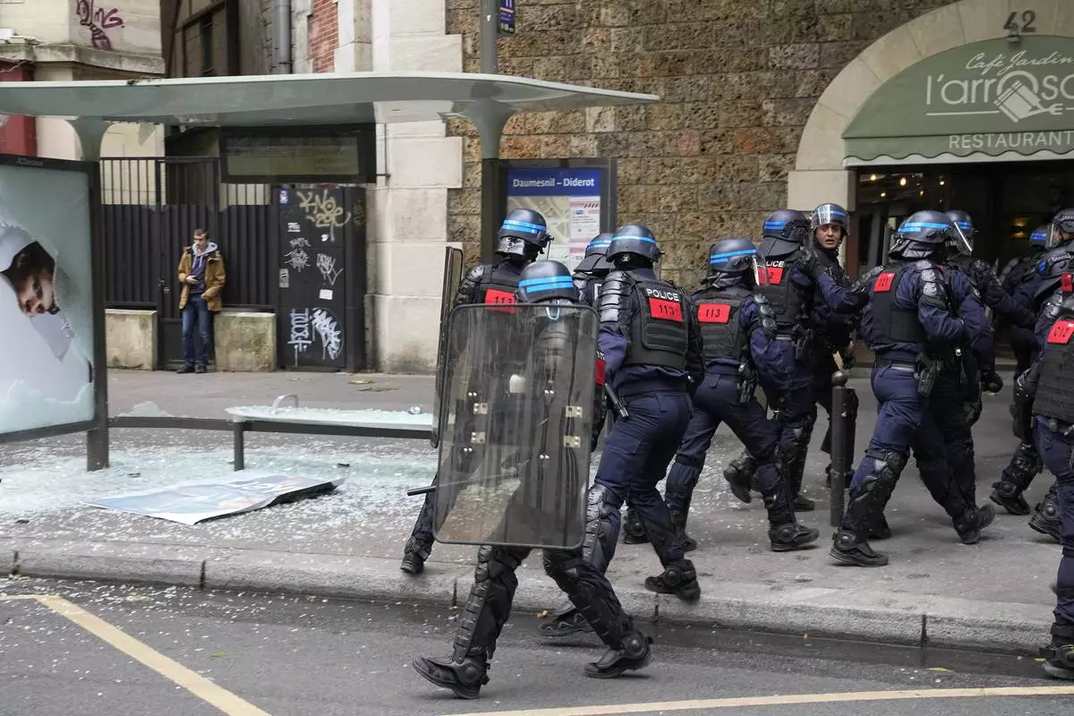 Police stand near a damaged bus shelter during a rally in Paris, Saturday, June 15, 2024. Antiracism groups will join French unions and a brand-new left-wing coalition in protests in Paris and across France on Saturday against the surging nationalist far right as frenzied campaigning is underway ahead of snap parliamentary elections. (AP Photo/Michel Euler)