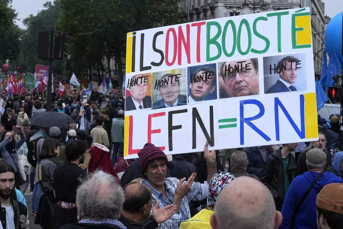 A protester holds an anti-far right banner showing the faces of French Presidents and the word 'Honte' or 'Shame' during a rally in Paris, Saturday, June 15, 2024. Anti-racism groups joined French unions and a brand-new left-wing coalition in protests in Paris and across France on Saturday against the surging nationalist far right as frenzied campaigning is underway ahead of snap parliamentary elections. (AP Photo/Michel Euler)