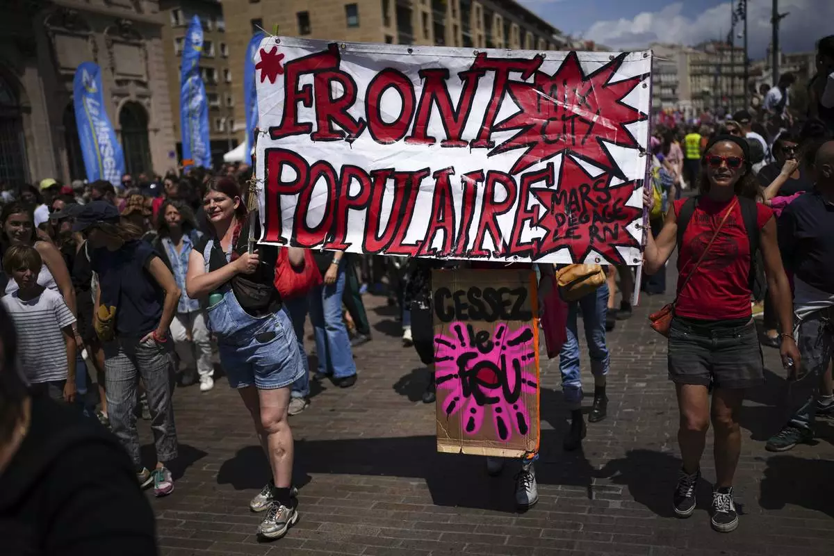 Protesters march with a banner that reads "Popular Front", during a demonstration in Marseille, southern France, Saturday, June 15, 2024. Anti-racism groups joined French unions and a brand-new left-wing coalition in protests in Paris and across France on Saturday against the surging nationalist far right as frenzied campaigning is underway ahead of snap parliamentary elections. (AP Photo/Daniel Cole)