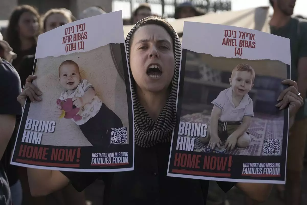 A woman holds posters of Kfir and Ariel Bibas, who are in Hamas captivity w...