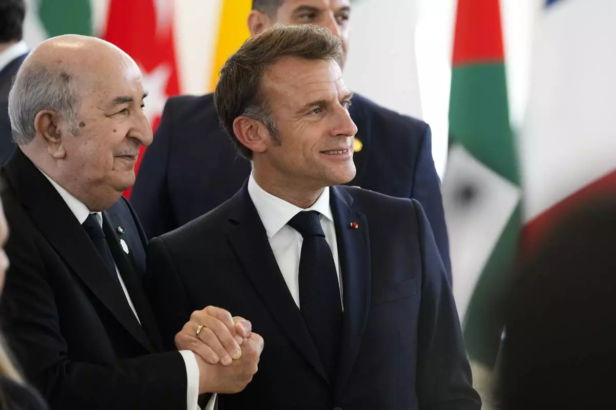 French President Emmanuel Macron, right shakes hands with Algerian President Abdelmadjid Tebboune during a working session on AI, Energy, Africa and Mideast at the G7 summit, in Borgo Egnazia, near Bari in southern Italy, Friday, June 14, 2024. (AP Photo/Andrew Medichini)