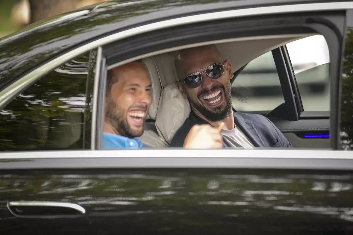 FILE - Andrew Tate, right, and his brother Tristan laugh as they leave the Bucharest Tribunal in Bucharest, Romania, May 8, 2024. English police accuse social media influencer Andrew Tate and his brother of being serial tax evaders in a civil court case in London. Police in Devon and Cornwall are seeking $3.6 million in unpaid taxes on earnings from their online businesses between 2014 and 2022. The Tates were not present for the hearing Tuesday July 9, 2024, in Westminster Magistrates’ Court. (AP Photo/Vadim Ghirda, File)