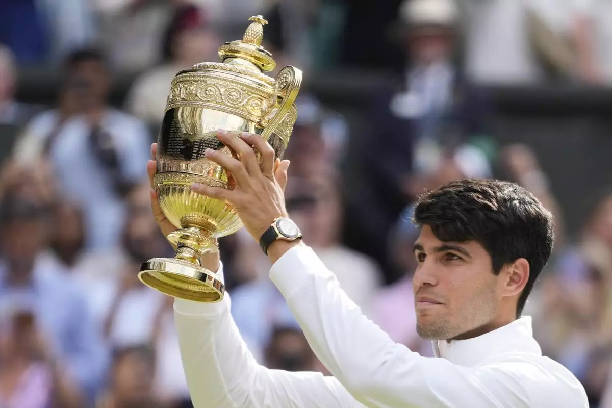 Carlos Alcaraz of Spain holds his trophy aloft after defeating Novak Djokovic of Serbia in the men's singles final at the Wimbledon tennis championships in London, Sunday, July 14, 2024. (AP Photo/Kirsty Wigglesworth)