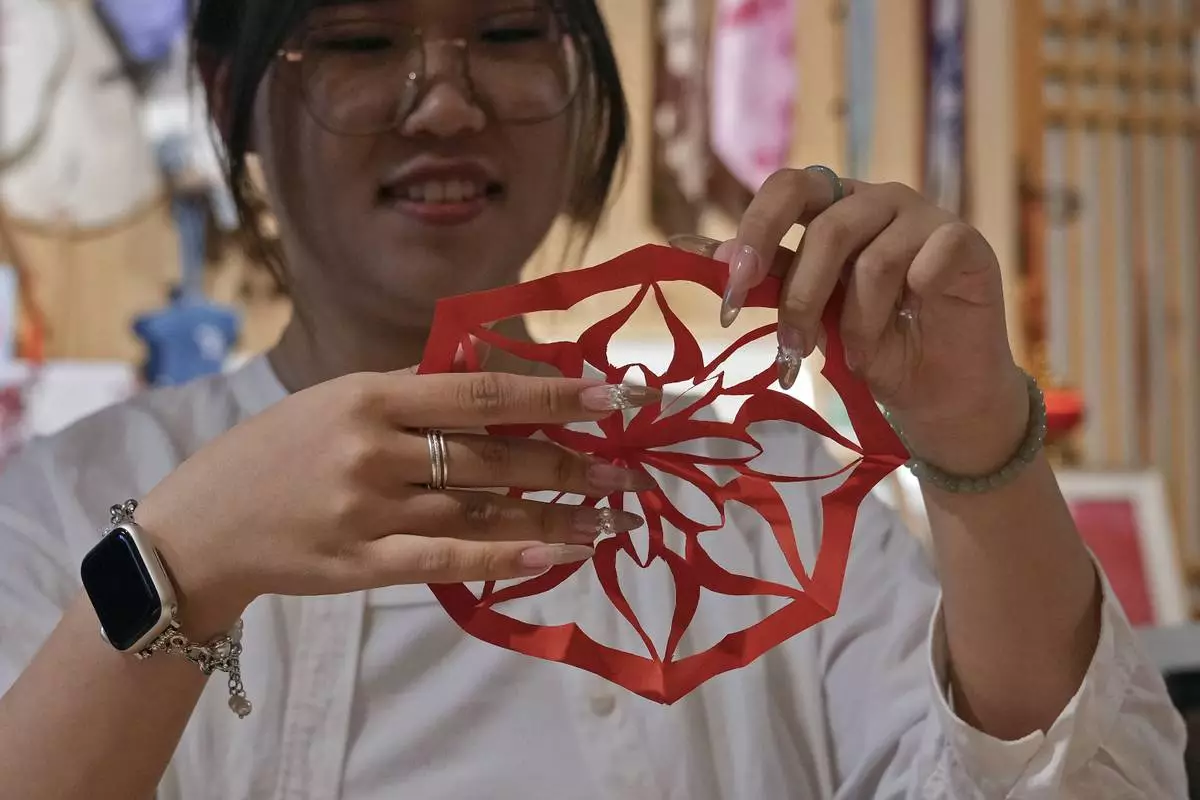 A university student shows a "nüshu" calligraphy paper cutting, at Xu Yan's Third Day Letter studio in Beijing on July 11, 2024. Nüshu is a centuries-old secret script. (AP Photo/Andy Wong)