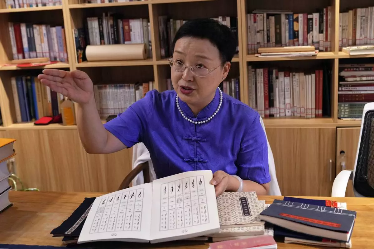 Xu Yan, an author of a textbook on nüshu, a centuries-old secret script, shows a book of nüshu calligraphy to the visiting university students at her studio in Beijing on July 11, 2024. (AP Photo/Andy Wong)