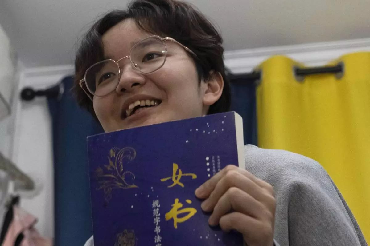 Lu Sirui, a 24-year-old working as a marketer, holds up a book with the word for nüshu, a centuries-old secret script, during an interview in Beijing, March 18, 2024. (AP Photo/Olivia Zhang)