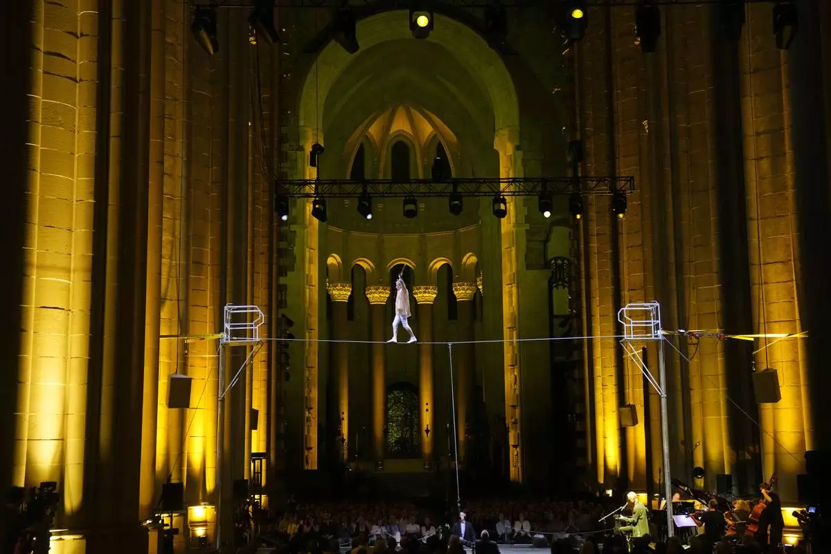 Philippe Petit walks a tightrope inside the Cathedral Church of St. John the Divine to mark the 50th anniversary of his World Trade Center Twin Towers high-wire walk, on Wednesday, Aug. 7, 2024, in New York. (Photo by Charles Sykes/Invision/AP)