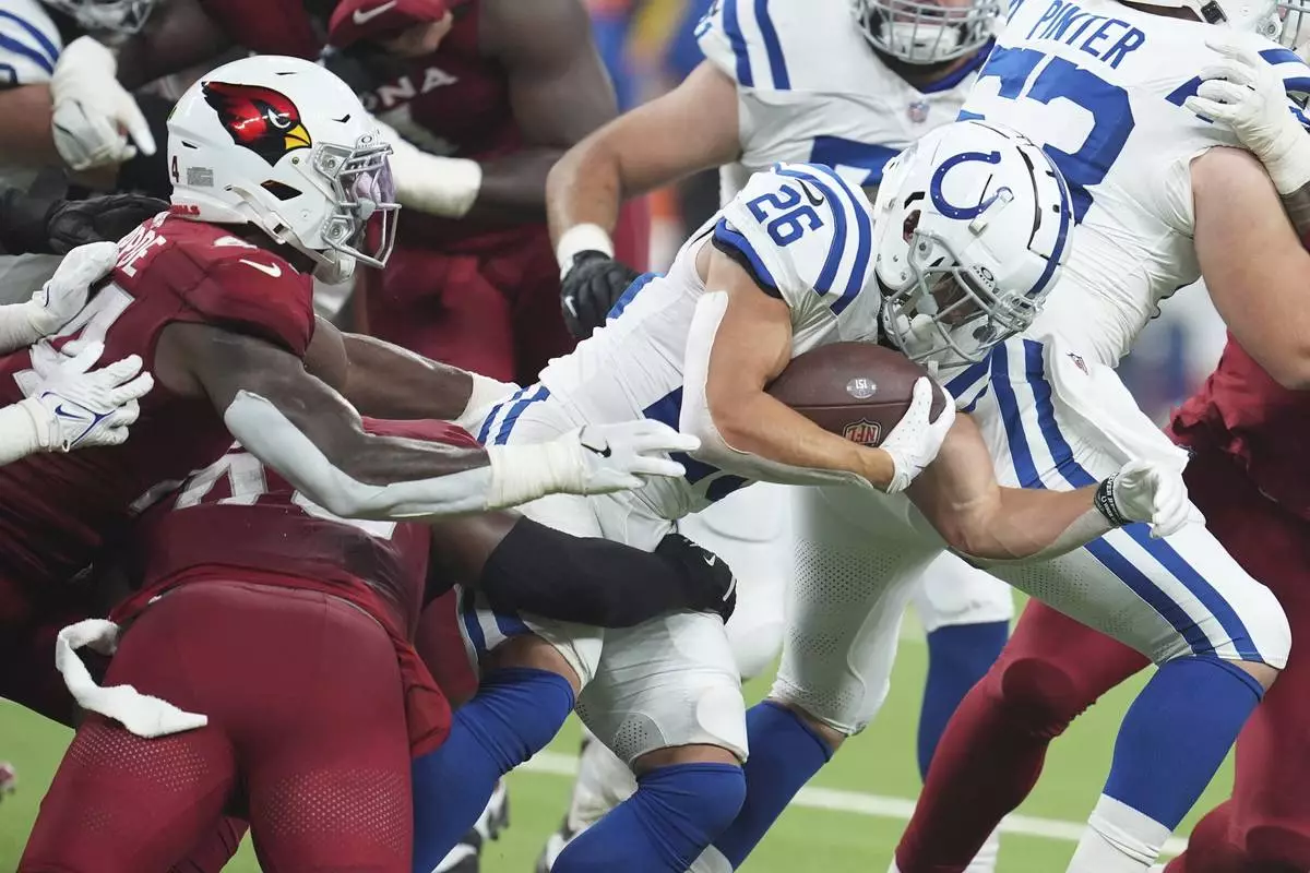 Indianapolis Colts running back Evan Hull (26) gets tackled by Arizona Cardinals linebacker Owen Pappoe, left, and Cardinals safety Dadrion Taylor-Demerson during the first half of a preseason NFL football game, Saturday, Aug. 17, 2024, in Indianapolis. (AP Photo/Michael Conroy)
