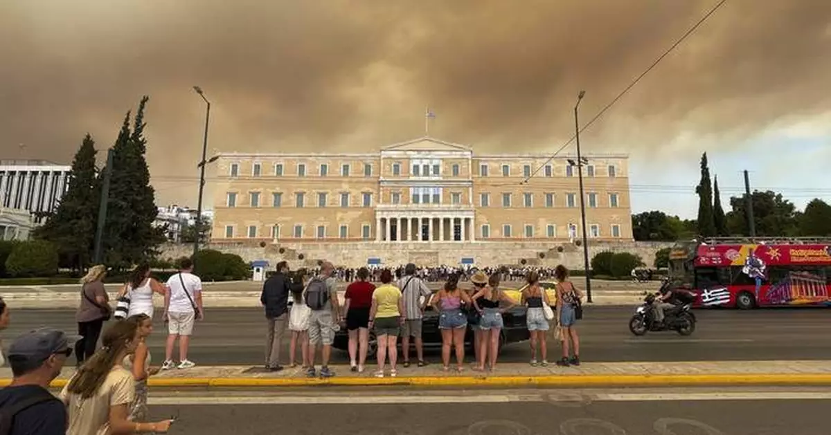 A wildfire near Greece's capital darkens the skies over Athens and advances fast