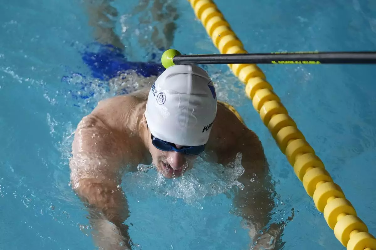 Teenage swimmer David Kratochvil is tapped by his father Jiri during his training in Tachov, Czech Republic, Wednesday, July 3, 2024. (AP Photo/Petr David Josek)
