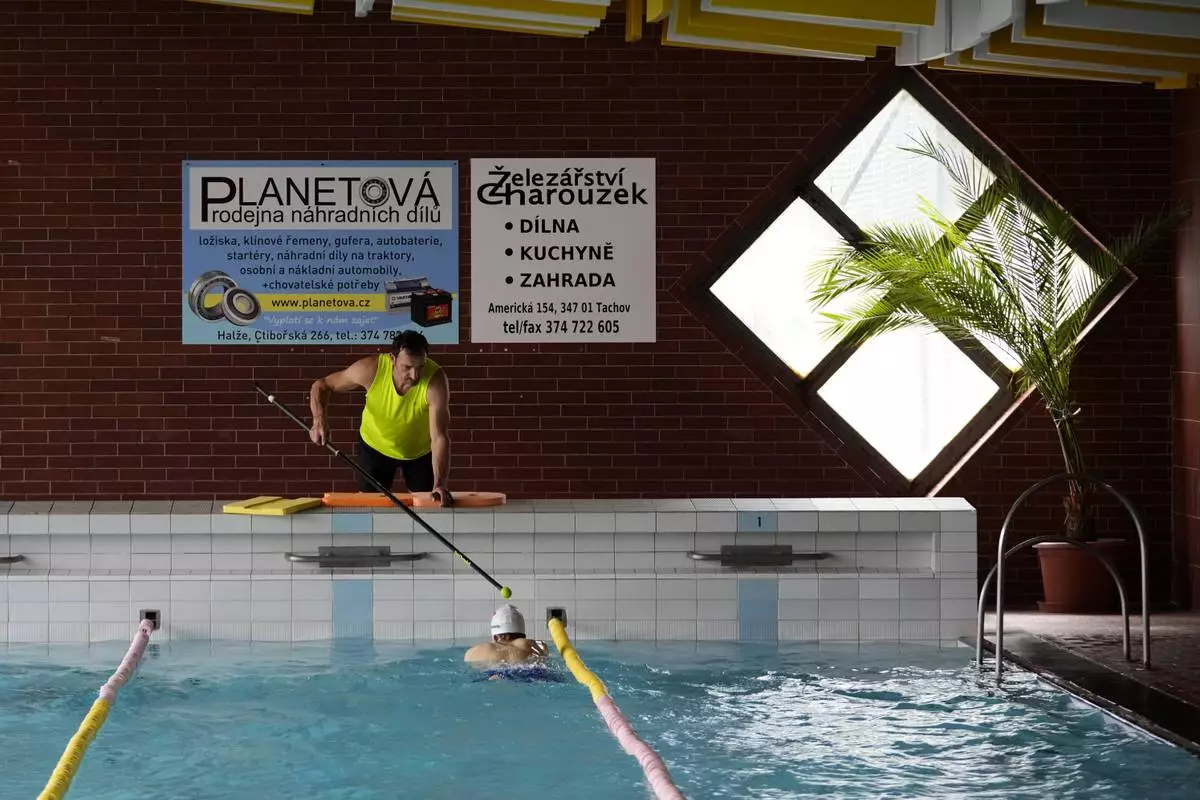 Teenage swimmer David Kratochvil is tapped by his father Jiri during his training in Tachov, Czech Republic, Wednesday, July 3, 2024. (AP Photo/Petr David Josek)