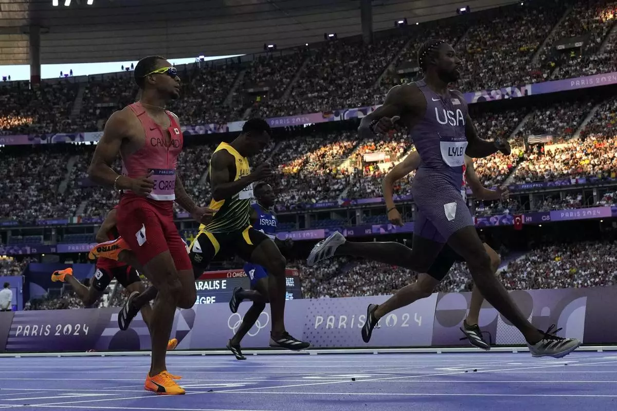 Noah Lyles, of the United States, crosses the finish line ahead of Andre de Grasse, left, of Canada, to win his men's 200-meters' heat at the 2024 Summer Olympics, Monday, Aug. 5, 2024, in Saint-Denis, France. (AP Photo/David J. Phillip)