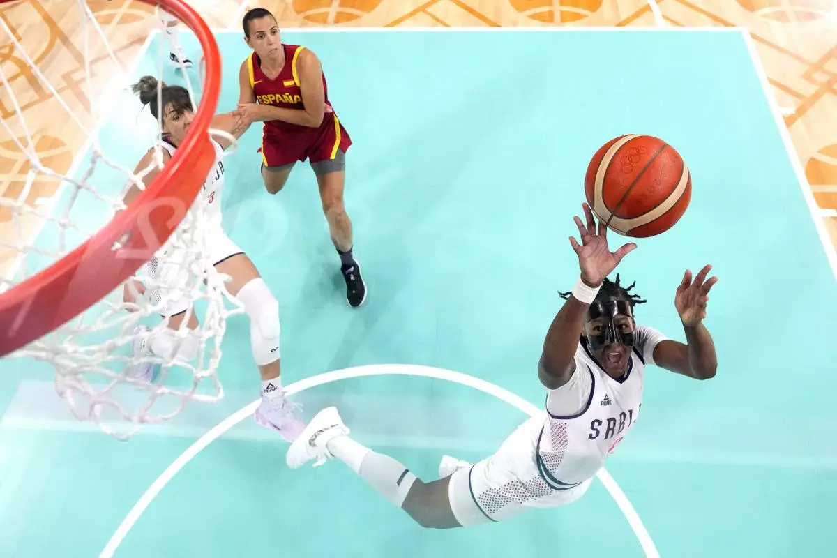 Serbia's Yvonne Anderson, right, shoots as Spain's Andrea Vilaro, center, defends and Serbia's Tina Kajisnik watches at the 2024 Summer Olympics, Saturday, Aug. 3, 2024, in Villeneuve-d'Ascq, France. (AP Photo/Michael Conroy, Pool)