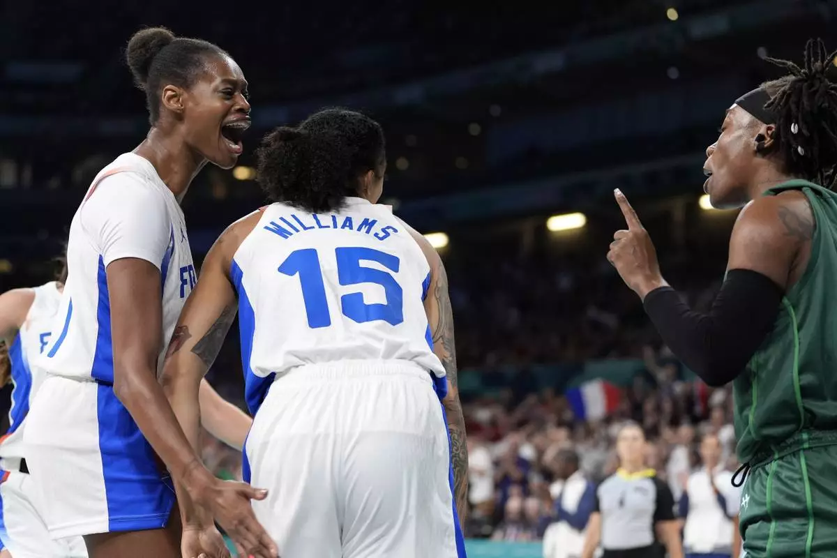 France's Valeriane Ayayi, left, celebrates after scoring and drawing a foul as Nigeria's Amy Ezinne Kalu has words with her with France's Gabby Williams between them during a women's basketball game at the 2024 Summer Olympics, Thursday, Aug. 1, 2024, in Villeneuve-d'Ascq, France. (AP Photo/Michael Conroy)