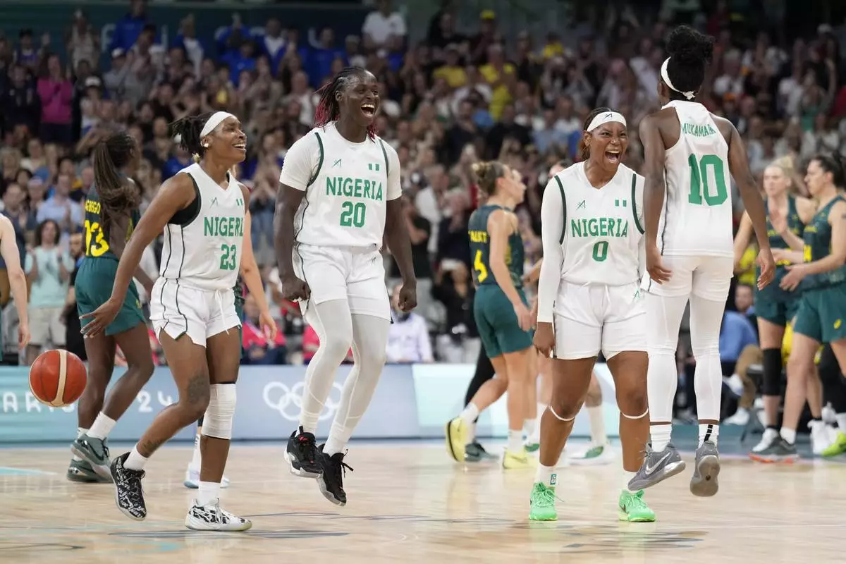 Nigerian players, left to right, Ezinne Kalu, Murjanatu Musa, Amy Okonkwo, of Nigeria, and Promise Amukamara, celebrate after Nigeria defeated Australia in a women's basketball game at the 2024 Summer Olympics, Monday, July 29, 2024, in Villeneuve-d'Ascq, France. (AP Photo/Mark J. Terrill)