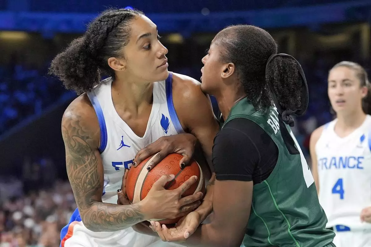 France's Gabby Williams, left, and Nigeria's Amy Elizabeth Balogun tie up the ball during a women's basketball game at the 2024 Summer Olympics, Thursday, Aug. 1, 2024, in Villeneuve-d'Ascq, France. (AP Photo/Michael Conroy)