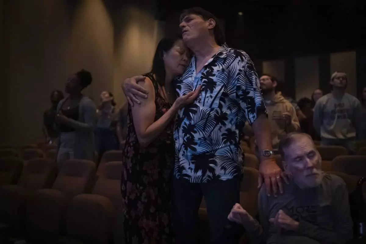 Lesley Dzik, left, and her husband, Matt, embrace each other while praying with Richard Wellbank at The Vineyard Church in Urbana, Ill., Sunday, Sept. 22, 2024. Lesley, a Republican, and Matt, a Democrat, have navigated issues common to so many marriages, from parenting to money. But politics? That's complicated. (AP Photo/David Goldman)