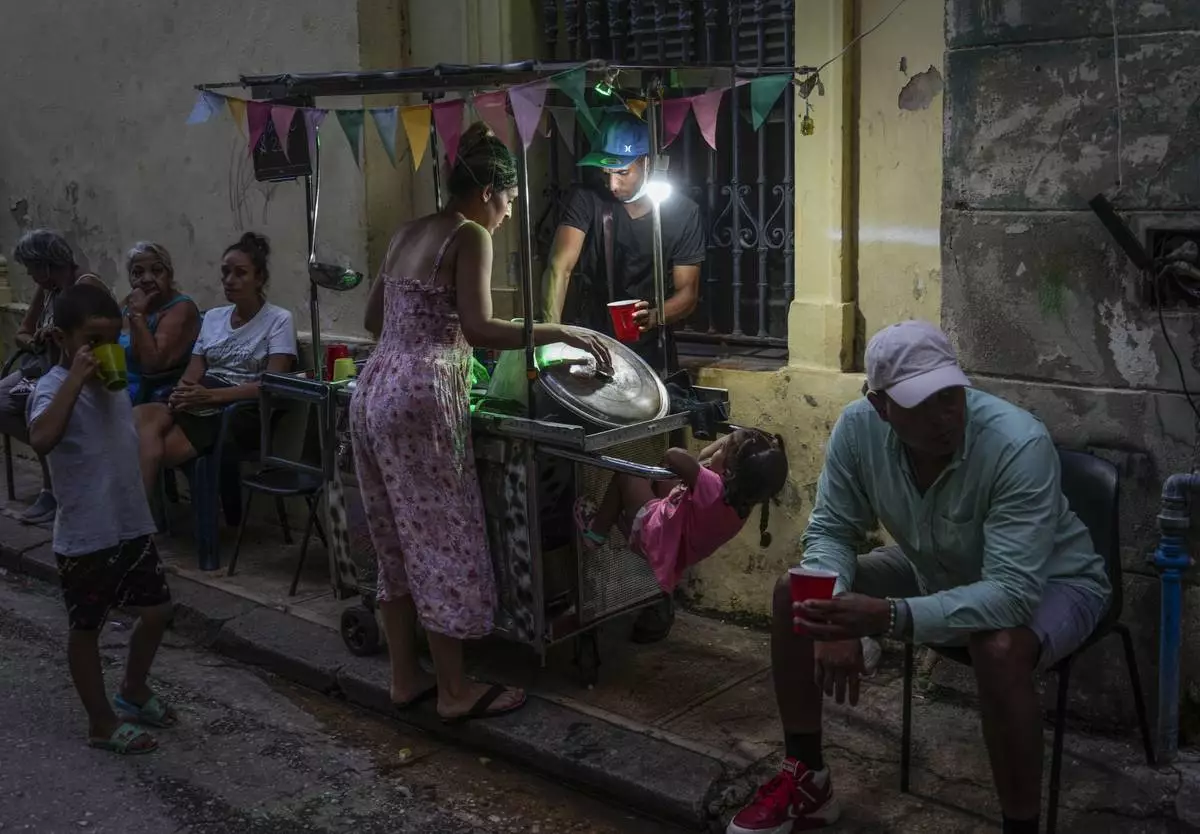 A woman buys soup from a street vendor during a power outage in Havana, Monday, Oct. 21, 2024. (AP Photo/Ramon Espinosa)