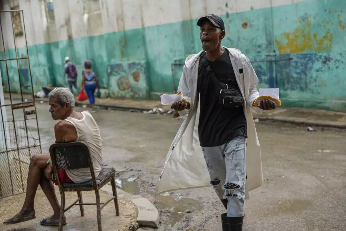 A man walks down the street holding slices of pizza during a massive blackout following the failure of a major power plant in Havana, Cuba, Saturday, Oct. 19, 2024. (AP Photo/Ramon Espinosa)