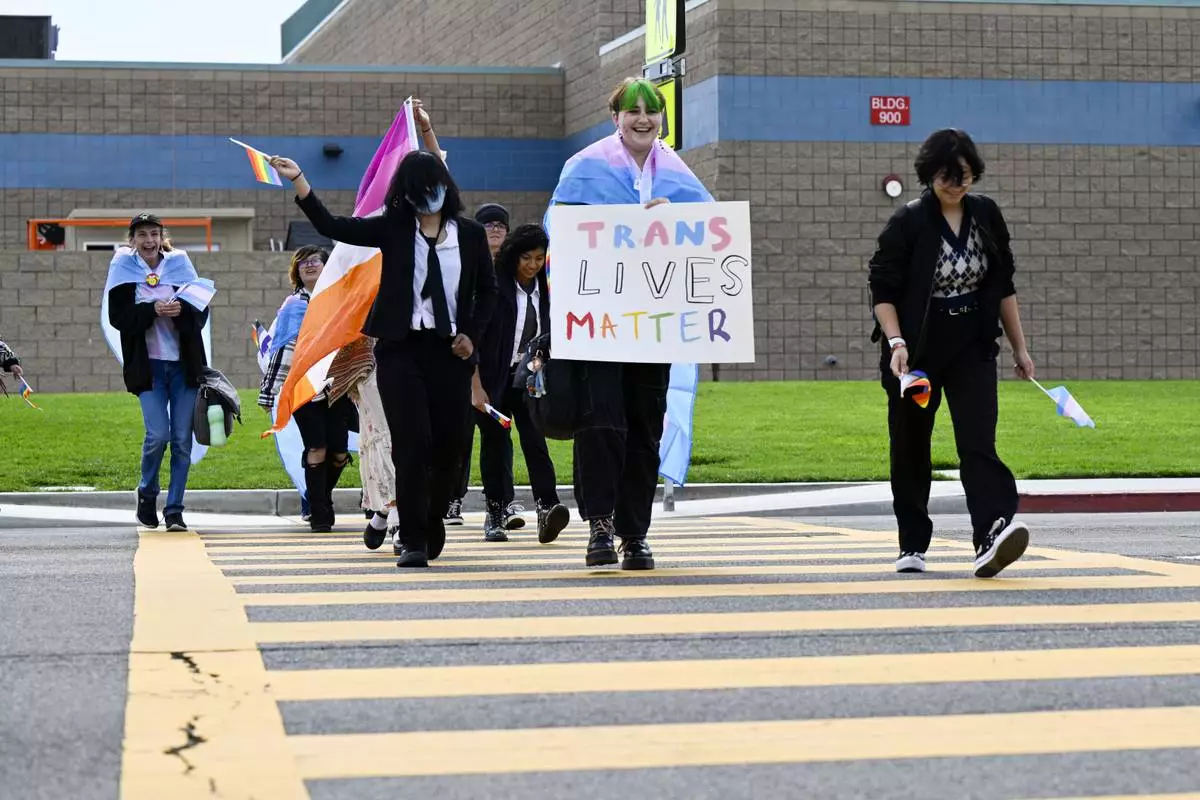 FILE - Students carrying pride and transgender flags leave Great Oak High School in Temecula, Calif., Friday, Sept. 22, 2023, after walking out of the school in protest of the Temecula school district policy requiring parents to be notified if their child identifies as transgender. (Anjali Sharif-Paul/The Orange County Register via AP, File)