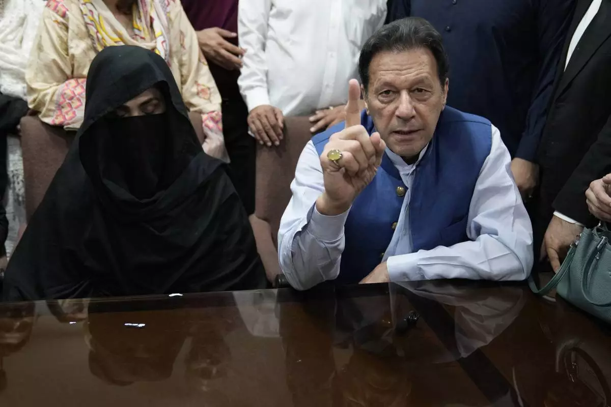 FILE - Pakistan's former Prime Minister Imran Khan, right, and Bushra Bibi, his wife, speak to the media before signing documents to submit surety bond over his bails in different cases, at an office of Lahore High Court in Lahore, Pakistan, on July 17, 2023. (AP Photo/K.M. Chaudary, File)