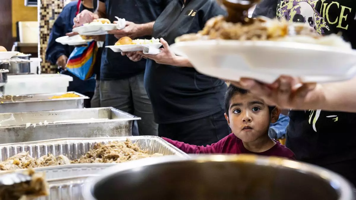 Three-year-old Alex Belman watches as his family members get their free turkey dinner at Harry's Cafe in Stanton, Calif. on Thursday, November 28, 2024. (Paul Bersebach/The Orange County Register via AP)