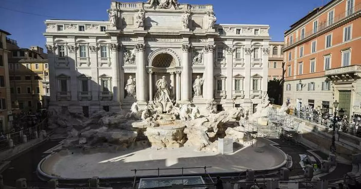 Tourists toss coins over a makeshift pool as Rome’s Trevi Fountain undergoes maintenance