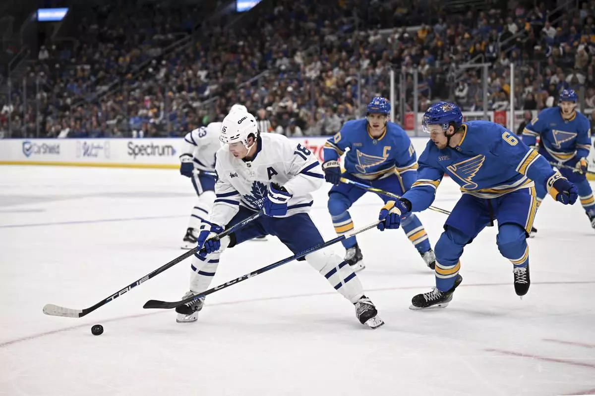 Toronto Maple Leafs' Mitch Marner (15) controls the puck as St. Louis Blues' Phillip Broberg (6) defends during the first period of an NHL hockey game Saturday, Nov. 2, 2024, in St. Louis. (AP Photo/Connor Hamilton)