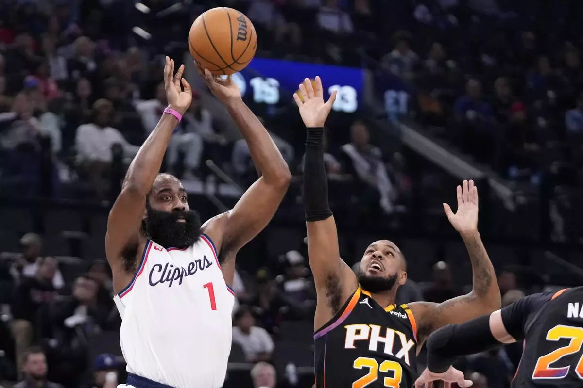 Los Angeles Clippers guard James Harden, left, passes the ball while under pressure from Phoenix Suns guard Monte Morris during the first half of an NBA basketball game, Thursday, Oct. 31, 2024, in Inglewood, Calif. (AP Photo/Mark J. Terrill)