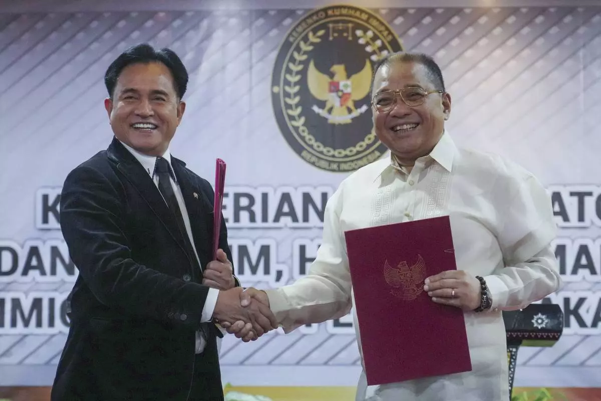 Indonesia's Coordinating Minister for Legal, Human Rights, Immigration and Correctional Affairs Yusril Ihza Mahendra, left, shakes hands with Philippine's Justice Undersecretary Raul Vasquez during the signing ceremony of a deal to send home Mary Jane Veloso, a Filipino death-row drug convict, in Jakarta, Indonesia, Friday, Dec. 6, 2024. (AP Photo/Tatan Syuflana)