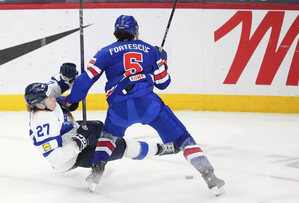 United States defenseman Drew Fortescue (5) pushes Finland forward Julius Miettinen (27) to the ice and picks up a penalty on the play during third-period IIHF World Junior Hockey Championship tournament game action in Ottawa, Ontario, Sunday, Dec. 29, 2024. (Sean Kilpatrick/The Canadian Press via AP)