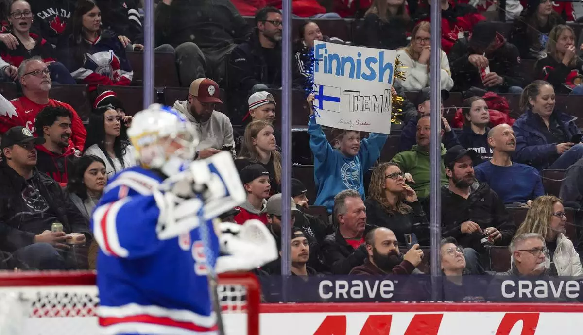 A young Finland fan holds a sign behind United States goaltender Trey Augustine (1) during second-period IIHF World Junior Hockey Championship tournament game action in Ottawa, Ontario, Sunday, Dec. 29, 2024. (Sean Kilpatrick/The Canadian Press via AP)