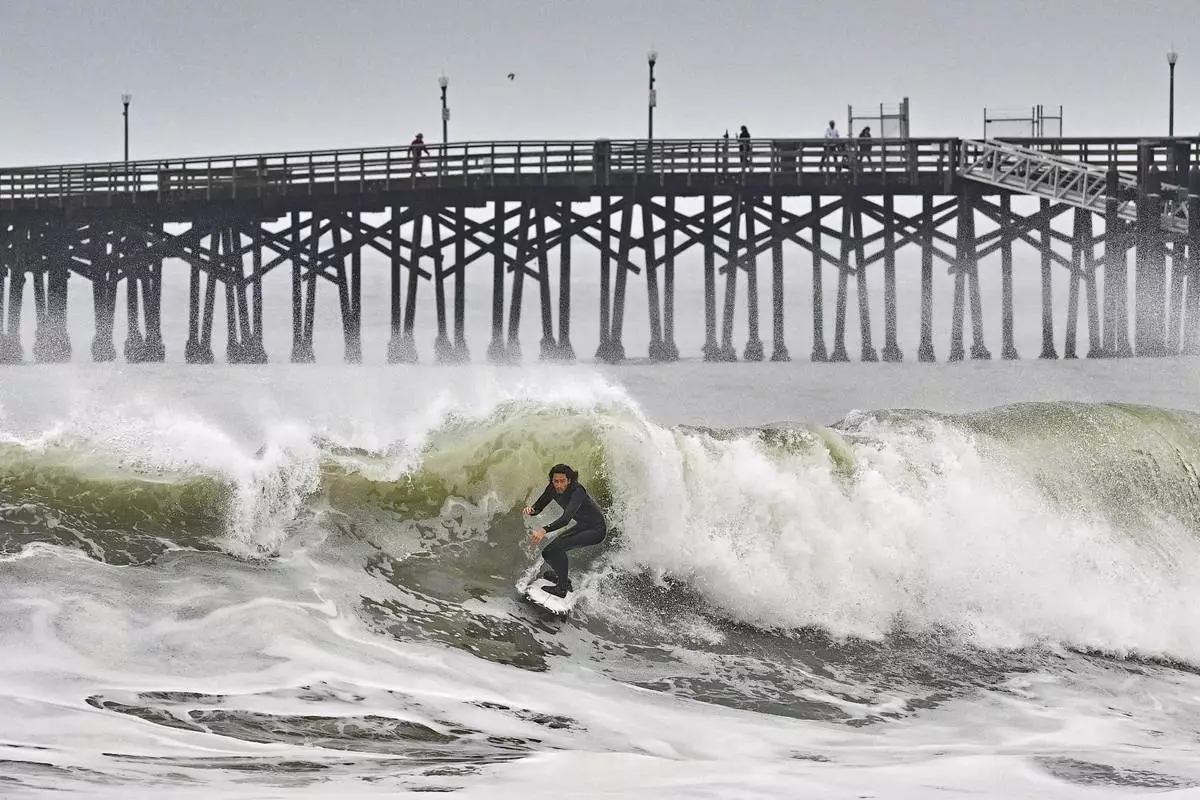 A surfer rides a wave at Seal Beach, Calif., Monday, Dec. 23, 2024. (Jeff Gritchen/The Orange County Register via AP)