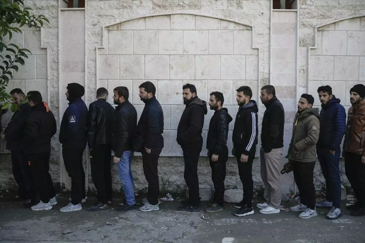 Members of Bashar Assad's army or pro-government militias line up to register with Syrian rebels as part of an "identification and reconciliation" process at an army compound in Latakia, Syria, Tuesday, Dec. 17, 2024. (AP Photo/Leo Correa)