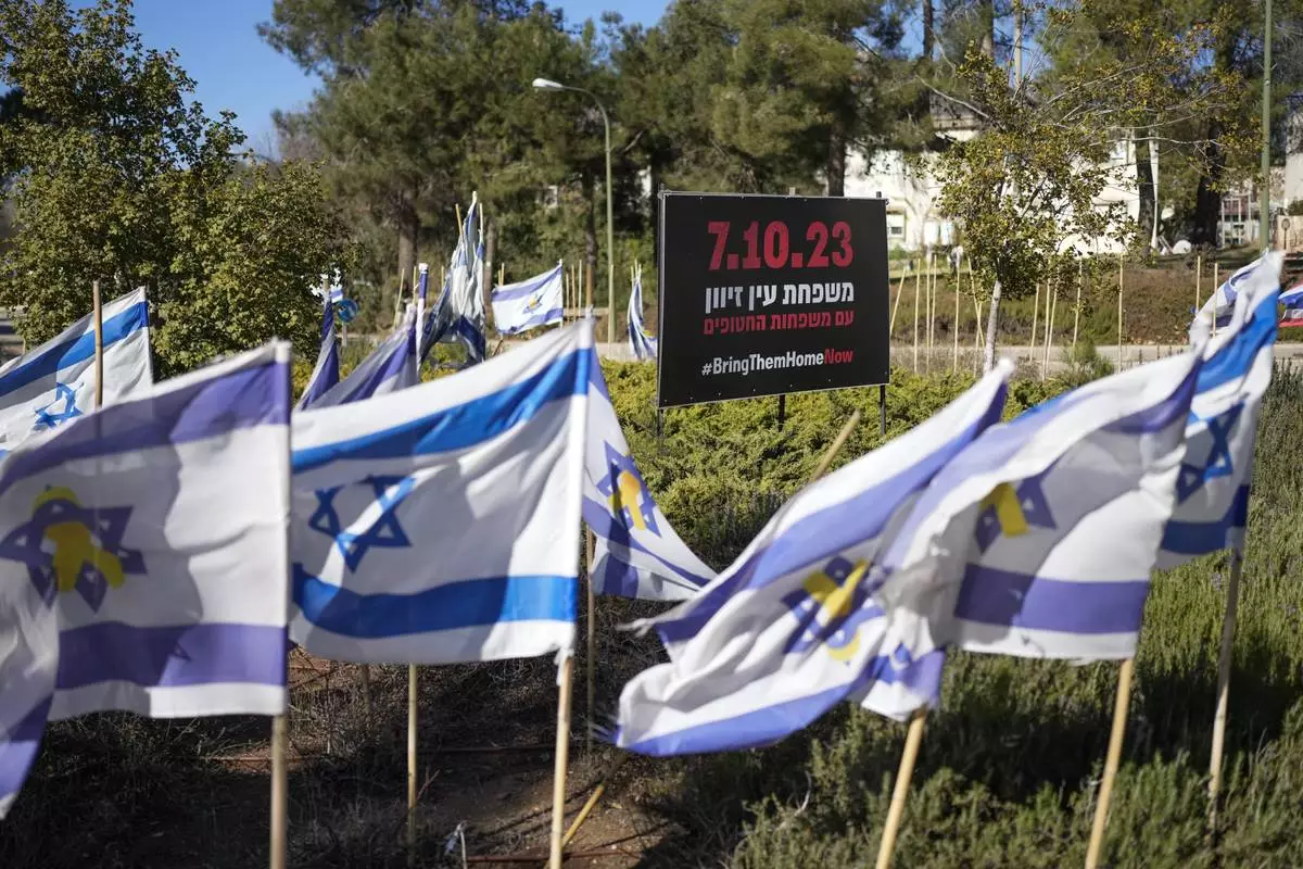 Israeli flags fly next to a sign in Hebrew that reads, "The families of Ein Zivan with the families of the hostages," in the kibbutz of Ein Zivan in the Israeli-annexed Golan Heights, which most of the world considers occupied Syrian territory, Thursday, Dec. 19, 2024. (AP Photo/Matias Delacroix)