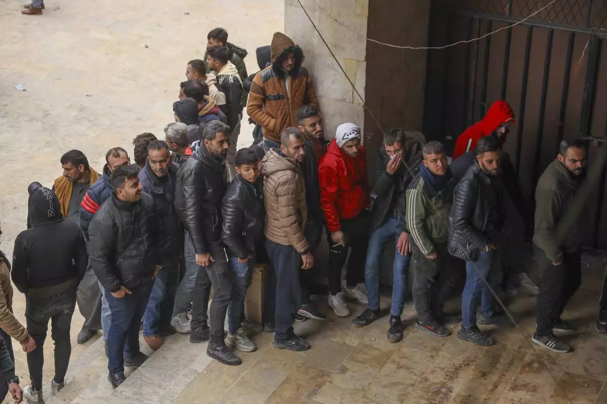 Defectors line-up to register their details with Syrian insurgents in Aleppo, Syria, Thursday Dec. 5, 2024. As insurgents consolidate their hold of Aleppo, which they overran last week, they issued a call to government soldiers and security agencies to defect, granting them what they called "protection cards," which offer them some sort of amnesty and assurances that they won't be hunted down.(AP Photo/Omar Albam)