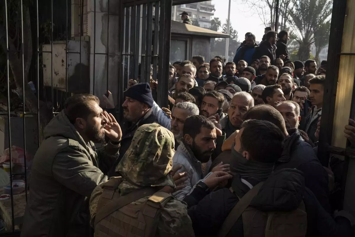 Members of Bashar Assad's army, or a pro-government militia, gather to be registered with Syrian rebels as part of an "identification and reconciliation process" in Damascus, Syria, Saturday, Dec. 21, 2024. (AP Photo/Leo Correa)