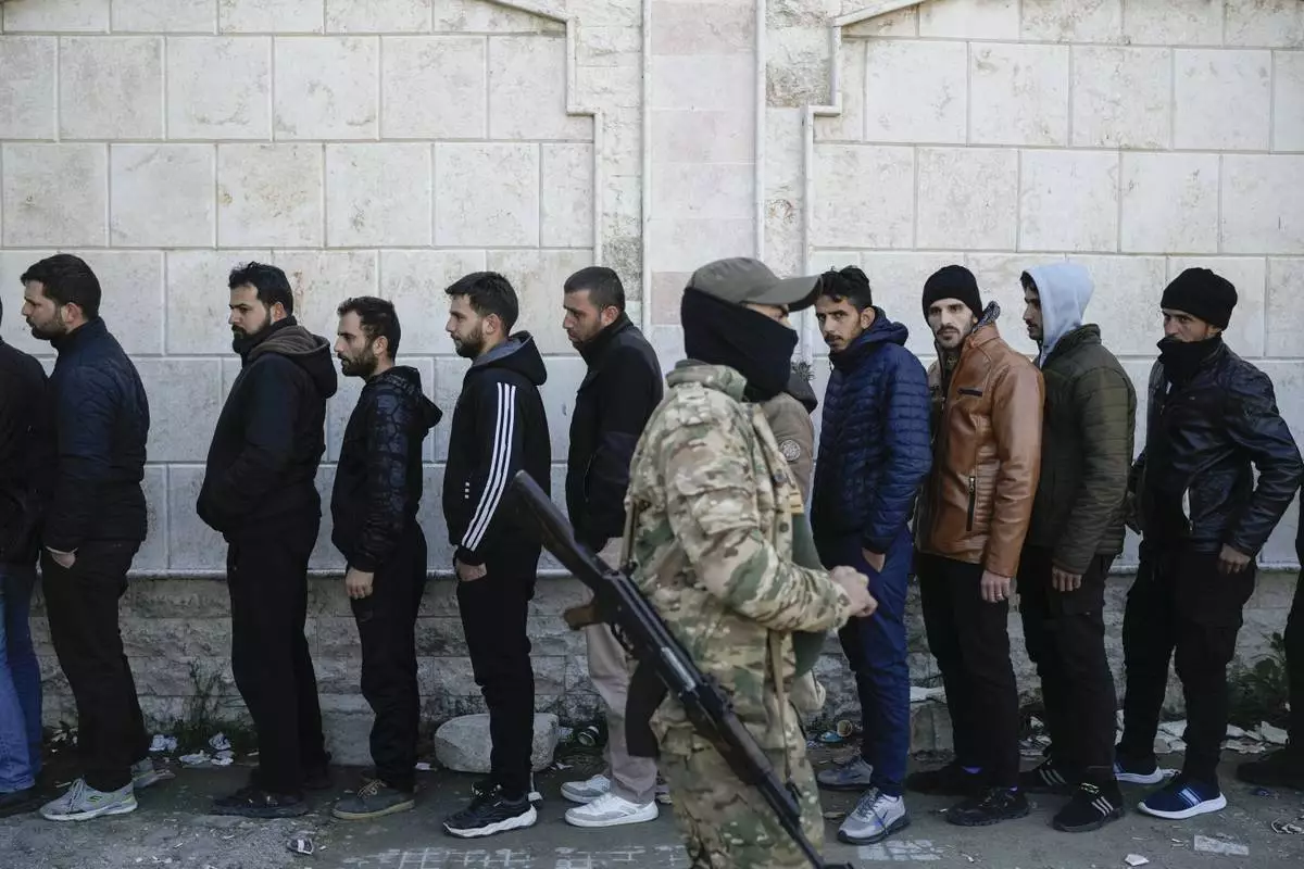 FILE - Members from Bashar Assad's Syrian army period line up to register with Syrian rebels as part of a "identification and reconciliation process" at a army compound in Latakia, Syria, Tuesday, Dec. 17, 2024. (AP Photo/Leo Correa, File)