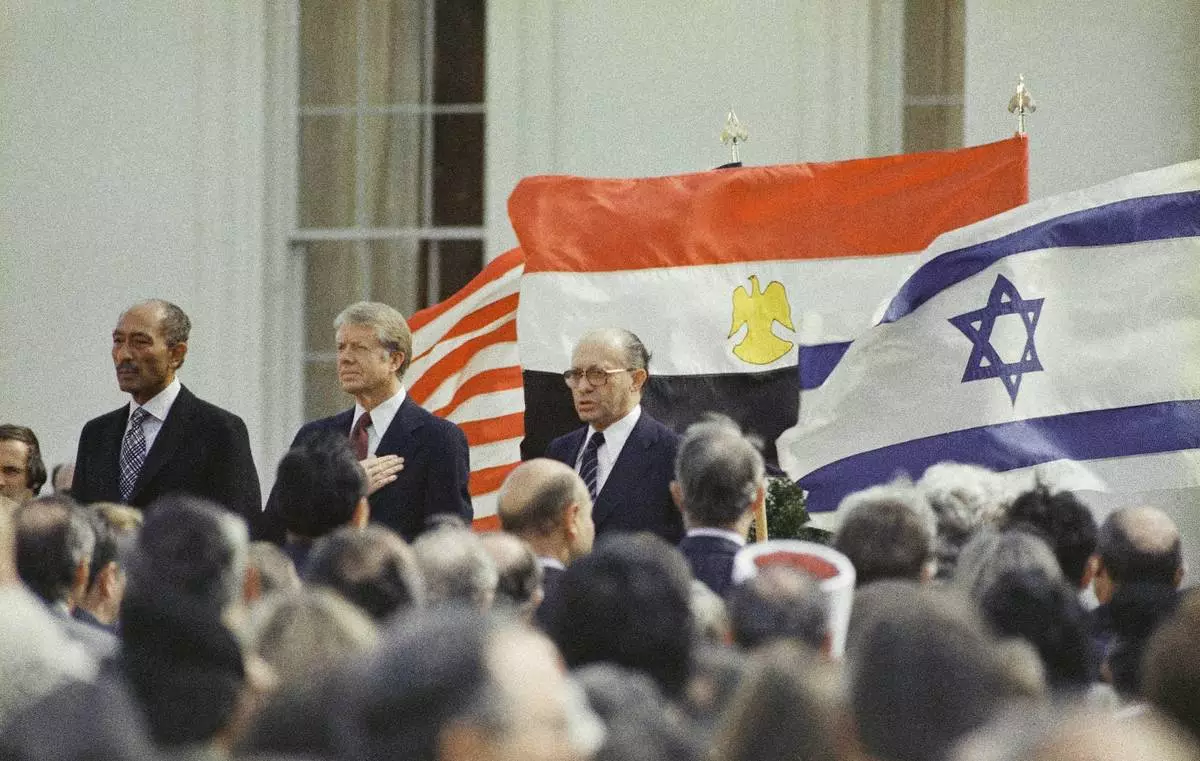 FILE - U.S. President Jimmy Carter, center, Egyptian President Anwar Sadat, left, and Israeli Prime Minister Menachem Begin stand in front of the billowing national flags of the U.S., Egypt and Israel, as the national anthems are played before the signing of the peace treaty between Israel and Egypt at the White House in Washington, March 26, 1979. (AP Photo, File)