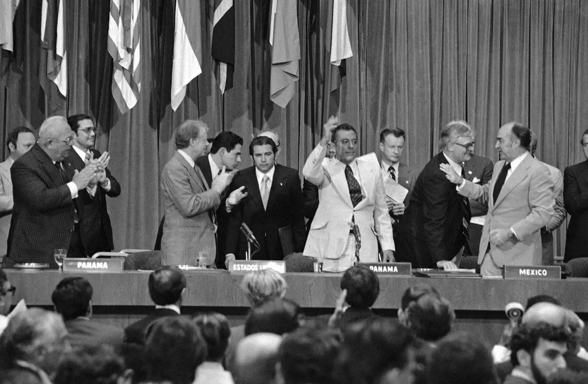 FILE - President Jimmy Carter applauds as General Omar Torrijos waves after the signing and exchange of treaties in Panama City on June 16, 1978, giving control of the Panama Canal to Panama in 2000. At far right is Zbigniew Brzezinski, Carterís National Security Advisor. (AP Photo, File)