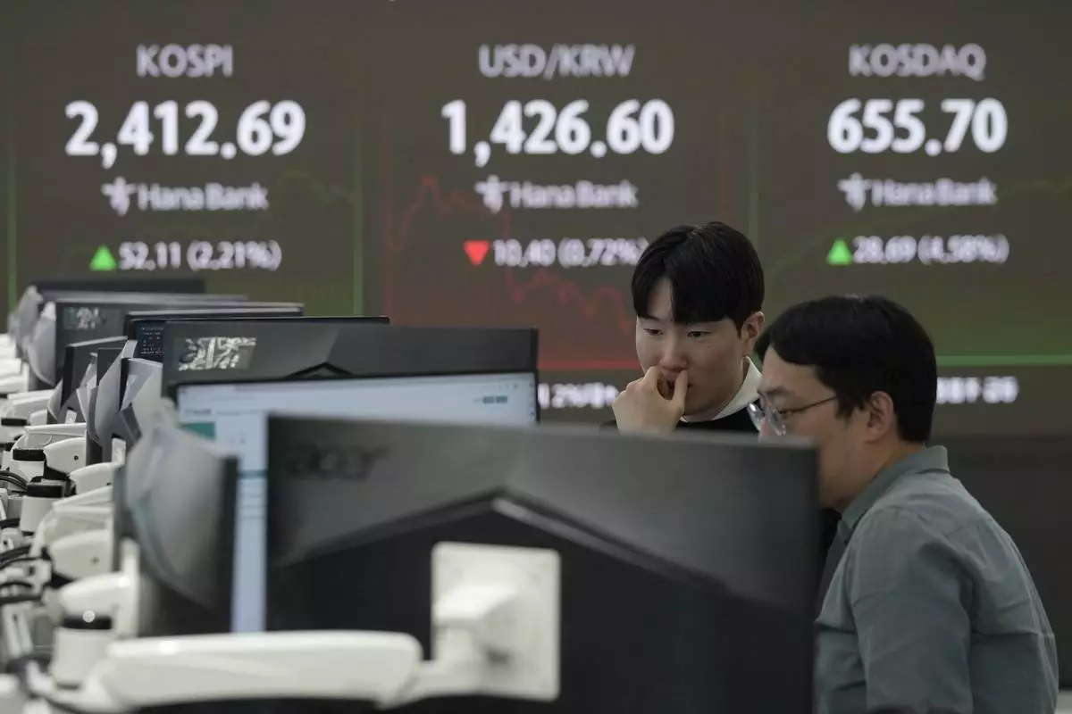 Currency traders watch monitors near a screen showing the Korea Composite Stock Price Index (KOSPI), top left, and the foreign exchange rate between U.S. dollar and South Korean won, top center, at the foreign exchange dealing room of the KEB Hana Bank headquarters in Seoul, South Korea, Tuesday, Dec. 10, 2024. (AP Photo/Ahn Young-joon)