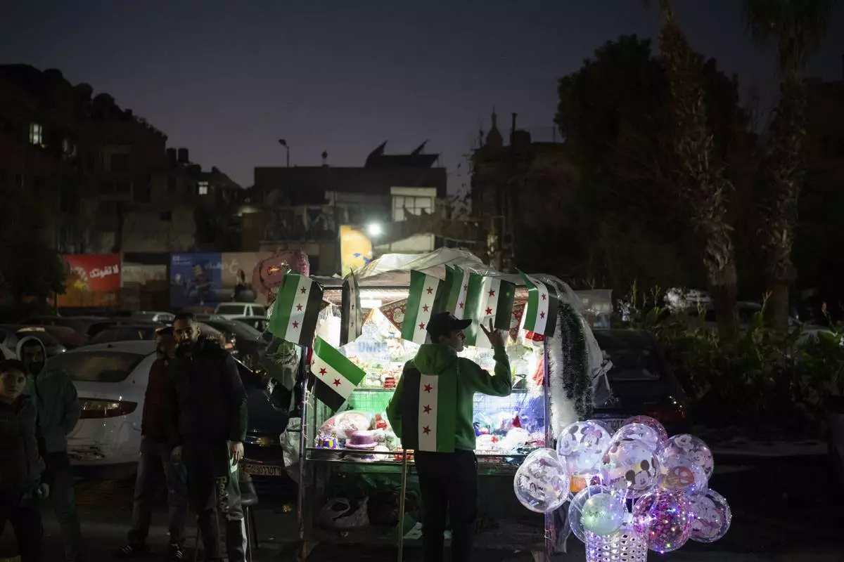 A street vendor flashes a victory sign in the Bab Touma neighborhood in the Old City of Damascus, Syria, Saturday, Dec. 14, 2024. (AP Photo/Leo Correa)