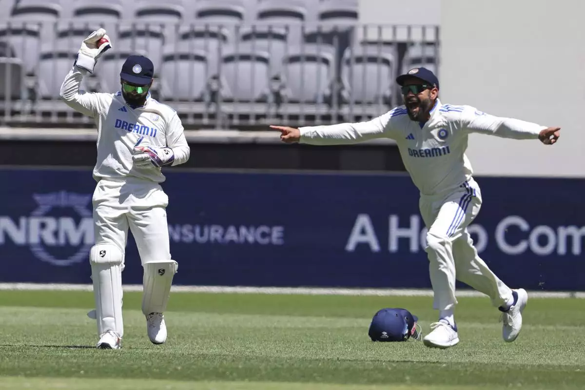 India's Virat Kohli, right, celebrates the wicket of Australia's Travis Head after Rishabh Pant, left, took the catch on the fourth day of the first cricket test between Australia and India in Perth, Australia, Monday, Nov. 25, 2024. (AP Photo/Trevor Collens)