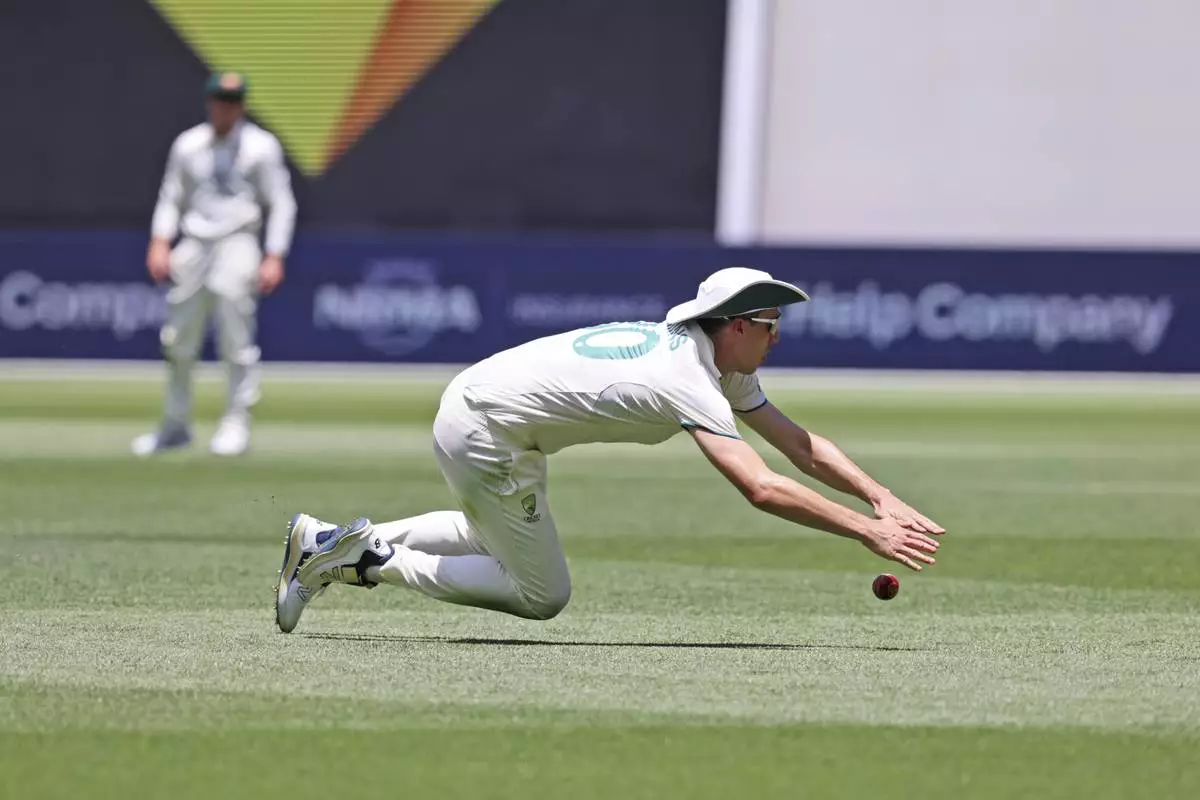 Australia's captain Pat Cummins dives to field the ball on the third day of the first cricket test between Australia and India in Perth, Australia, Sunday, Nov. 24, 2024. (AP Photo/Trevor Collens)