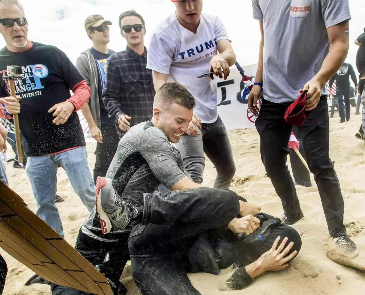 Robert Paul Rundo, of Huntington Beach, holds down and punches a counter-protester at a political rally at Bolsa Chica State Beach in Huntington Beach, Calif. March 25, 2017. (Mindy Schauer/The Orange County Register via AP)