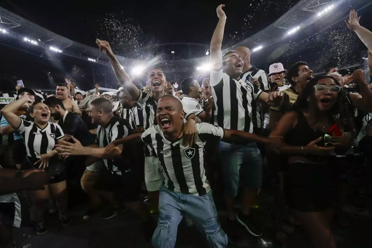 Botafogo soccer fans celebrate their team's third goal scored by Junior Santos against Atletico Mineiro in the Copa Libertadores title match in Argentina, broadcast on a giant screen at a watch party at the Nilton Santos Stadium, in Rio de Janeiro, Saturday, Nov. 30, 2024. (AP Photo/Bruna Prado)