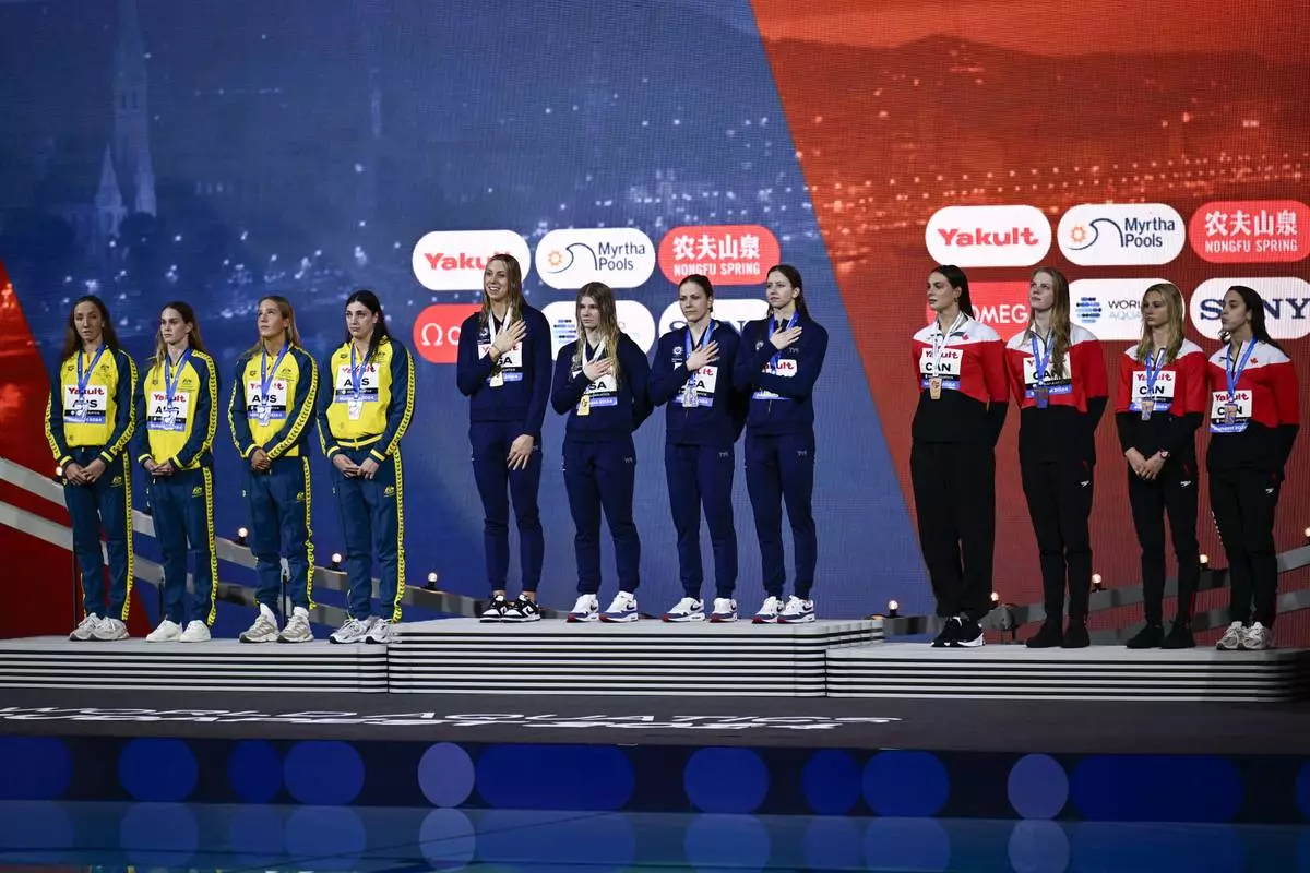 From the left second-placed Australia, first-placed United States, and third-placed Canada teams stand on the podium after 4x100 meter freestyle final during the World Short Course Swimming Championships in Budapest, Hungary, Tuesday, Dec. 10, 2024. (AP Photo/Denes Erdos)