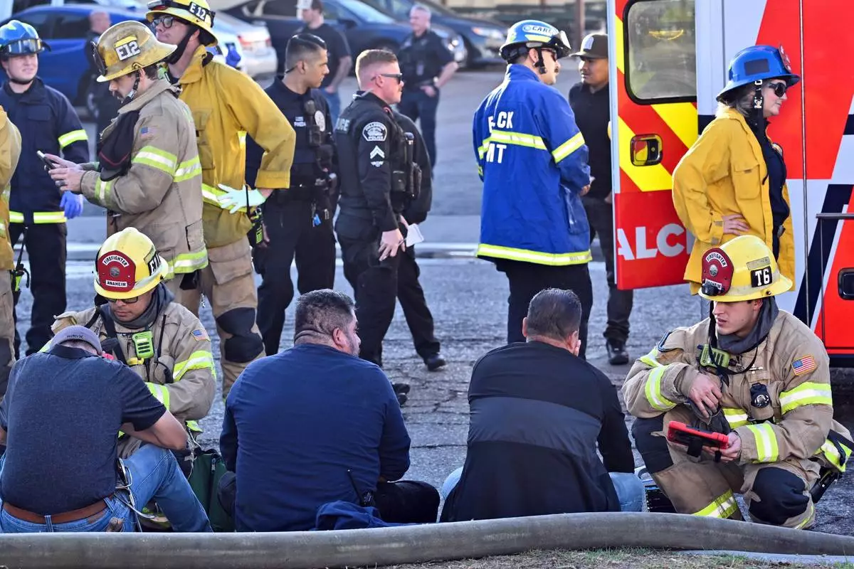 Firefighters tend to people after a plane crashed through the roof of a building near Fullerton airport on Thursday, Jan. 2, 2025, in Fullerton, Calif. (Jeff Gritchen, Orange County Register/The Orange County Register via AP)